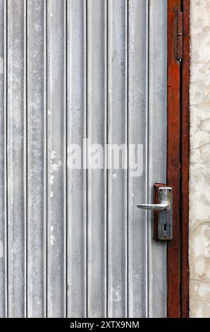 Vecchia porta in ferro galvanizzato, struttura in metallo Grunge, edificio con vernice bianca. Foto Stock