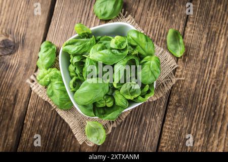 Porzione di basilico fresco (primo piano, messa a fuoco selettiva) su sfondo in legno Foto Stock