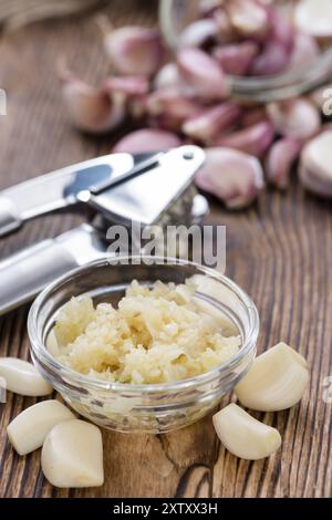 Aglio schiacciato (close-up shot) sul rustico sfondo di legno Foto Stock