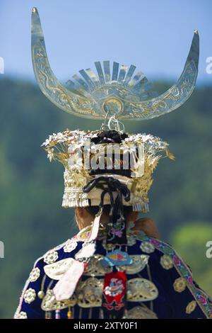 Xijiang, Cina, 15 settembre 2007: Vista posteriore della donna Miao della minoranza etnica in abiti da festa tradizionali e copricapo d'argento in piedi a Miao Vill Foto Stock