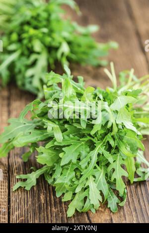 Tavolo in legno con rucola fresca come primo piano dettagliato (messa a fuoco selettiva) Foto Stock