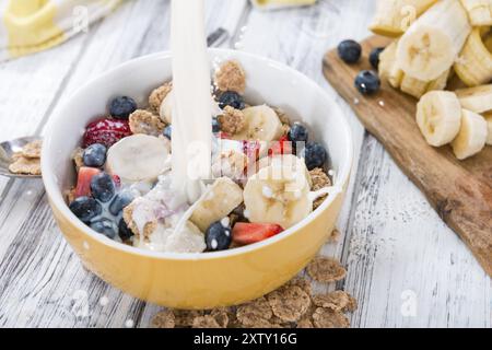 Corn flakes con frutta fresca e latte su un tavolo di legno Foto Stock