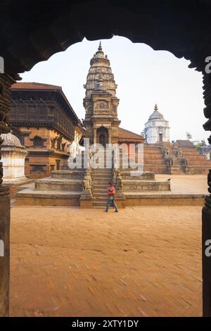 Bhaktapur, Nepal, 31 ottobre 2013: Donna nepalese che cammina di fronte al tempio Siddhi Laxmi intatto incorniciato da un arco in Bhaktapur Durbar Square Foto Stock