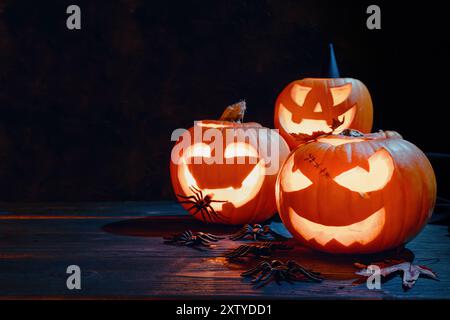 Gruppo di zucche scolpite, ragni e foglie autunnali, spettrale sfondo di Halloween, spazio copia Foto Stock