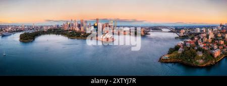 Panorama panoramico all'alba della città sul lungomare del porto di Sydney intorno al ponte del porto di Sydney da Kirribilli. Foto Stock