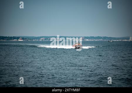 Un Response Boat di 45 piedi dalla stazione della Guardia Costiera di New London trasporta passeggeri verso la Guardia Costiera Cutter Eagle (WIX 327) durante un tour dei media a New London, CT, 15 agosto 2024. Eagle tornò a New London dopo un dispiegamento di 97 giorni come parte della sua missione estiva di addestramento per i cadetti della Guardia Costiera. Foto Stock