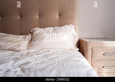 Camera accogliente con testiera beige e comò. Foto Stock