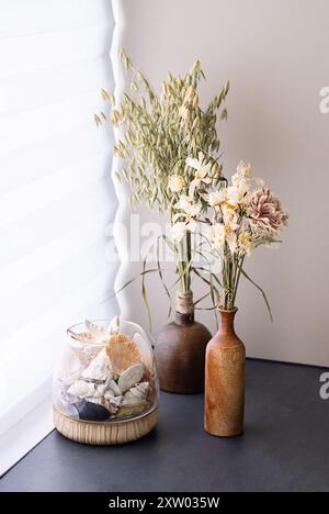 Composizioni floreali essiccate e conchiglie in vasi rustici su davanzale per finestra. Foto Stock