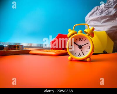 Orologio giallo da primo piano con prob studio su sfondo arancione e blu Foto Stock