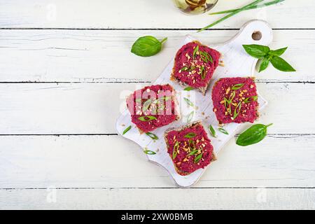 Tosta con barbabietola, noci tritate ed erbe aromatiche. Bruschetta vegana con barbabietola Foto Stock