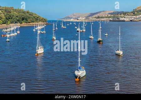 Vista dal ponte stradale di Conwy, nel Galles del Nord, degli yacht ormeggiati con la bassa marea nell'estuario e nella città di Llandudno sul lato superiore destro dell'immagine Foto Stock