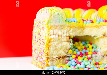 Una torta con spruzzette colorate e un buco nel mezzo. La torta viene tagliata in modo da rivelare un ripieno colorato Foto Stock