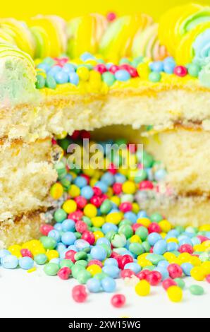 Una torta con spruzzette colorate e un buco nel mezzo. La torta viene tagliata in modo da rivelare un ripieno colorato Foto Stock
