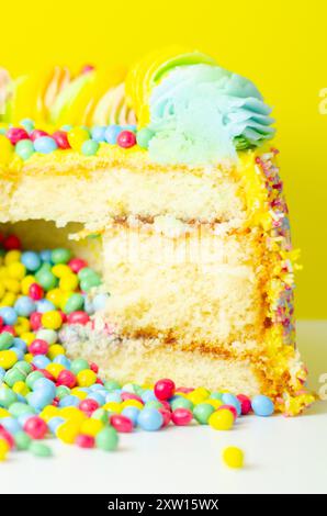 Una torta con spruzzette colorate e un buco nel mezzo. La torta viene tagliata in modo da rivelare un ripieno colorato Foto Stock