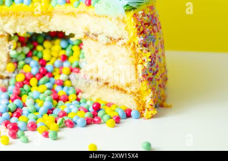 Una torta con spruzzette colorate e un buco nel mezzo. La torta viene tagliata in modo da rivelare un ripieno colorato Foto Stock