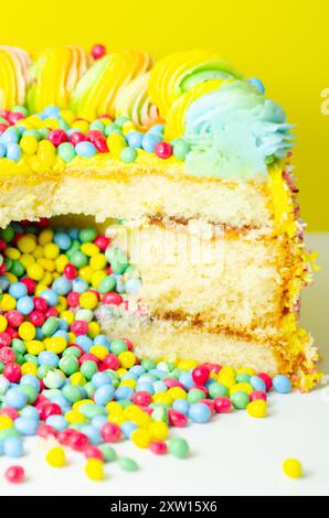 Una torta con spruzzette colorate e un buco nel mezzo. La torta viene tagliata in modo da rivelare un ripieno colorato Foto Stock