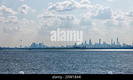 Nuvoloso, nebbioso, skyline di New York nel tardo pomeriggio, visto da Ferry Point/Throggs Neck, Bronx, con Rikers Island (prigione) in primo piano. Foto Stock