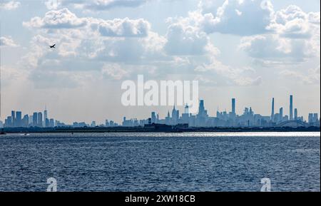 Nuvoloso, nebbioso, skyline di New York nel tardo pomeriggio, visto da Ferry Point/Throggs Neck, Bronx, con Rikers Island (prigione) in primo piano. Foto Stock