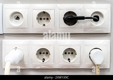 Prese elettriche su una parete bianca. Cavo elettrico inserito in una presa elettrica bianca su sfondo bianco. Una presa su una parete bianca. Alti quali Foto Stock