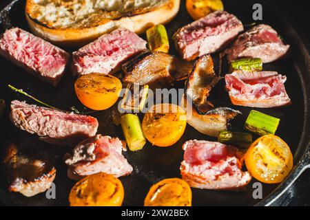 Il tonno viene scottato in una padella di ghisa con pomodori ciliegini, asparagi, pancetta e pane tostato. Foto di alta qualità Foto Stock