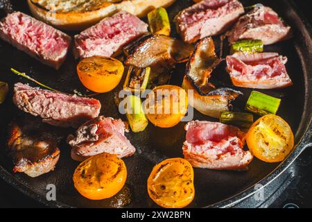 Il tonno viene scottato in una padella di ghisa con pomodori ciliegini, asparagi, pancetta e pane tostato. Foto di alta qualità Foto Stock