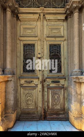 Vecchio portone in legno con ferro battuto arrugginito all'ingresso di una casa Foto Stock