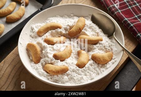 Cospargere i biscotti di Natale fatti in casa chiamati Kipferl di zucchero vanigliato Foto Stock