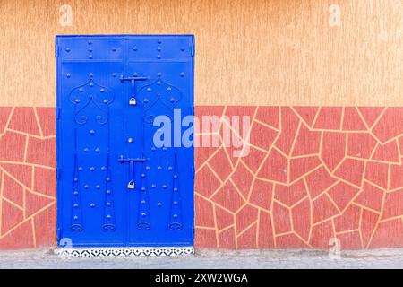 Porta di metallo blu su sfondo di una parete gialla con muratura dipinta Foto Stock