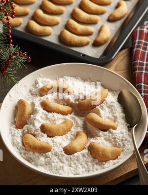 Cospargere di zucchero i biscotti di Natale fatti in casa chiamati Kipferl o le mezzalune di vaniglia Foto Stock