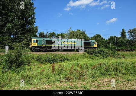 Il diesel Freightliner classe 66 dirige un treno di carri merci a sud verso Ely, Cambridgeshire, Inghilterra, Regno Unito Foto Stock