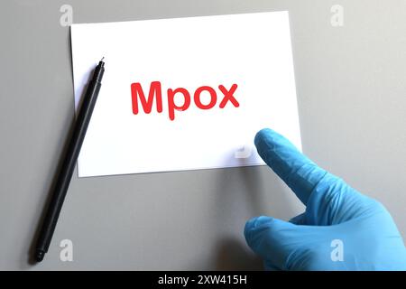 La mano del medico indica un foglio bianco con il testo "Mpox". Concetto per Mpox virus. Foto Stock