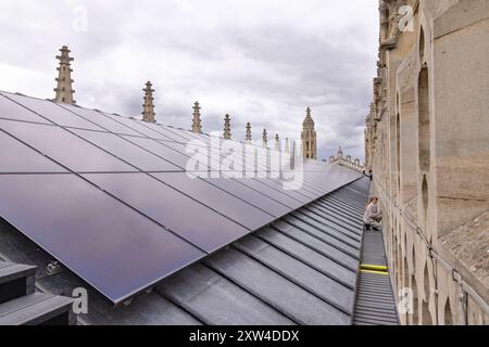 Un visitatore sul tetto della Cappella del Kings College come parte di un tour; pannelli solari installati per l'energia verde o solare; Kings College Cambridge Regno Unito. Foto Stock