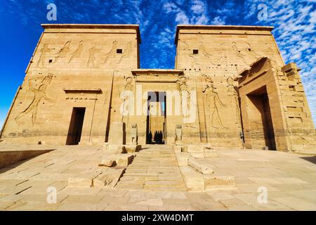 Gli imponenti piloni con rilievi murali raffiguranti Tolomeo, Iside e Horus contro un brillante cielo blu al Tempio di Iside sull'isola di file sul lago Nasser, costruito da Nectanebo e Tolomeo Pharoahs vicino ad Assuan, in Egitto Foto Stock