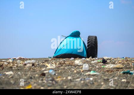 Tenda blu sulla spiaggia. Campeggio sulla riva del mare. Spazzatura sparsi intorno alla tenda. Foto Stock