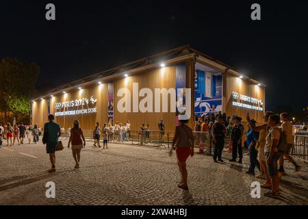 Parigi, Francia - 10 agosto 2024: La folla passa davanti alla boutique ufficiale Olympic Pop-up sugli Champs-Elysees di notte Foto Stock