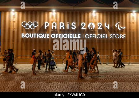 Parigi, Francia - 10 agosto 2024: La folla passa davanti alla boutique ufficiale Olympic Pop-up sugli Champs-Elysees di notte Foto Stock