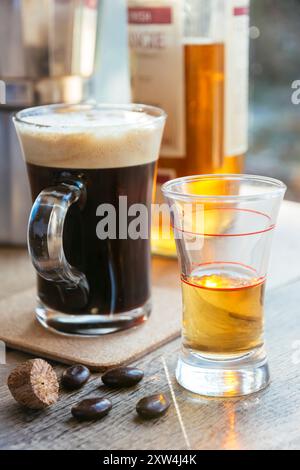 Tazza di caffè fresco e bicchiere da espresso con whisky per marcare il caffè irlandese. Nella parte anteriore, chicchi di caffè e noce moscata. Foto Stock