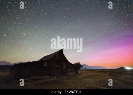 L'aurora boreale e il bagliore d'aria brillano con le stelle sopra il T.A. Moulton Barn lungo Mormon Row. Grand Teton National Park, Wyoming Foto Stock