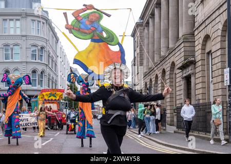 Belfast Mela multiculturale Carnival Parade - donna con insolita arte decorativa che partecipa alle feste del centro città. Belfast, Regno Unito - 17 agosto 2024. Foto Stock