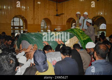 Srinagar, India. 17 agosto 2024. Gli uomini musulmani del Kashmir toccano la sacra tomba di Hazrat Sultan Sayed Muhammad 'Ali 'Ala Balkhi durante la cerimonia Poshakbandi a Pakherpora, che si trova a 43 chilometri da Srinagar, Kashmir, India, il 17 agosto 2024. Secondo la tradizione locale, Hazrat Sultan Sayed Muhammad 'Ali 'Ala Balkhi era ritenuto un discendente del profeta Maometto e governava la città di Millahin Balkh, che si trova nell'attuale Afghanistan. (Foto di Danish Showkat/Sipa USA.) Crediti: SIPA USA/Alamy Live News Foto Stock