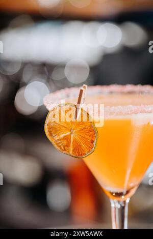 Primo piano di un vivace cocktail all'arancia guarnito con una fetta di agrumi secchi, perfetto per l'estate Foto Stock