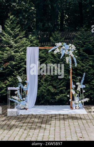 Elegante arco nuziale all'aperto con decorazioni floreali per una romantica cerimonia in giardino Foto Stock