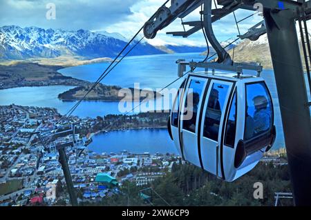 Gondola turistica si innalza al di sopra della cittadina di Queenstown, in Nuova Zelanda con il lago di Wakatipu in background. Foto Stock