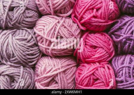 Palline di filato rosa e viola in deposito. Sfondo caldo in filato di lana. Hobby per lavorare a maglia. Fila di filati rosa. Negozio di lavoro. Unisci sfondo. Foto Stock