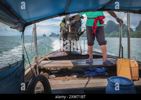 Phuket Thailandia ritratto dell'uomo che guida la barca in un giorno d'estate. I pescatori guidano una tradizionale barca tailandese a coda lunga in Thailandia. Foto di viaggio Foto Stock