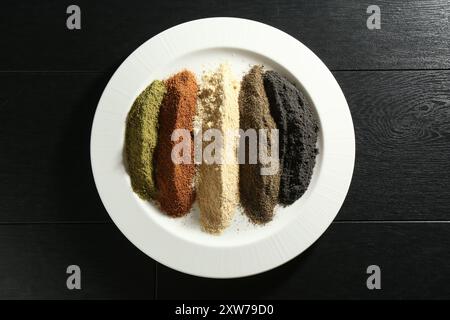 Diverse polveri di superfood sul tavolo di legno nero, vista dall'alto Foto Stock