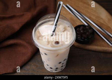 Saporito tè con bolle di latte in una tazza di plastica su un tavolo di legno, primo piano Foto Stock