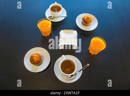 Colazione: due tazze di caffè, due succhi di arancia e due muffin. Vista da sopra. Foto Stock