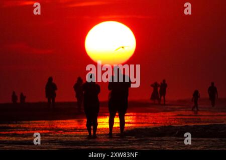 Isola di Palms, Stati Uniti. 18 agosto 2024. Gli amanti della spiaggia, che si stagliano dall'alba, osservano il sole che esce dall'orizzonte in un'altra giornata calda e umida sulla spiaggia di Wild Dunes, 18 agosto 2024, a Isle of Palms, South Carolina. I giorni continuano negli anni novanta e le temperature oceaniche superano i 83 gradi. Crediti: Richard Ellis/Richard Ellis/Alamy Live News Foto Stock