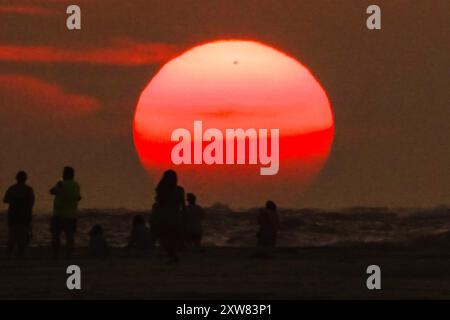 Isola di Palms, Stati Uniti. 18 agosto 2024. Gli amanti della spiaggia, che si stagliano dall'alba, osservano il sole che esce dall'orizzonte in un'altra giornata calda e umida sulla spiaggia di Wild Dunes, 18 agosto 2024, a Isle of Palms, South Carolina. I giorni continuano negli anni novanta e le temperature oceaniche superano i 83 gradi. Crediti: Richard Ellis/Richard Ellis/Alamy Live News Foto Stock